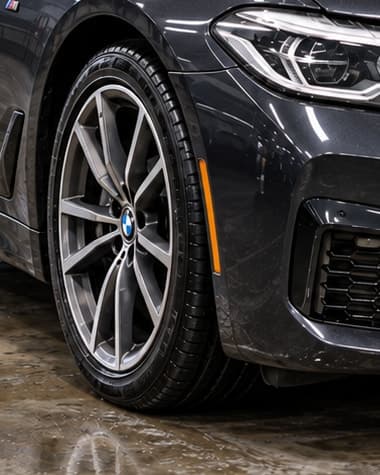 Očišćena felna i guma tamnog BMW automobila na mokrom podu studija